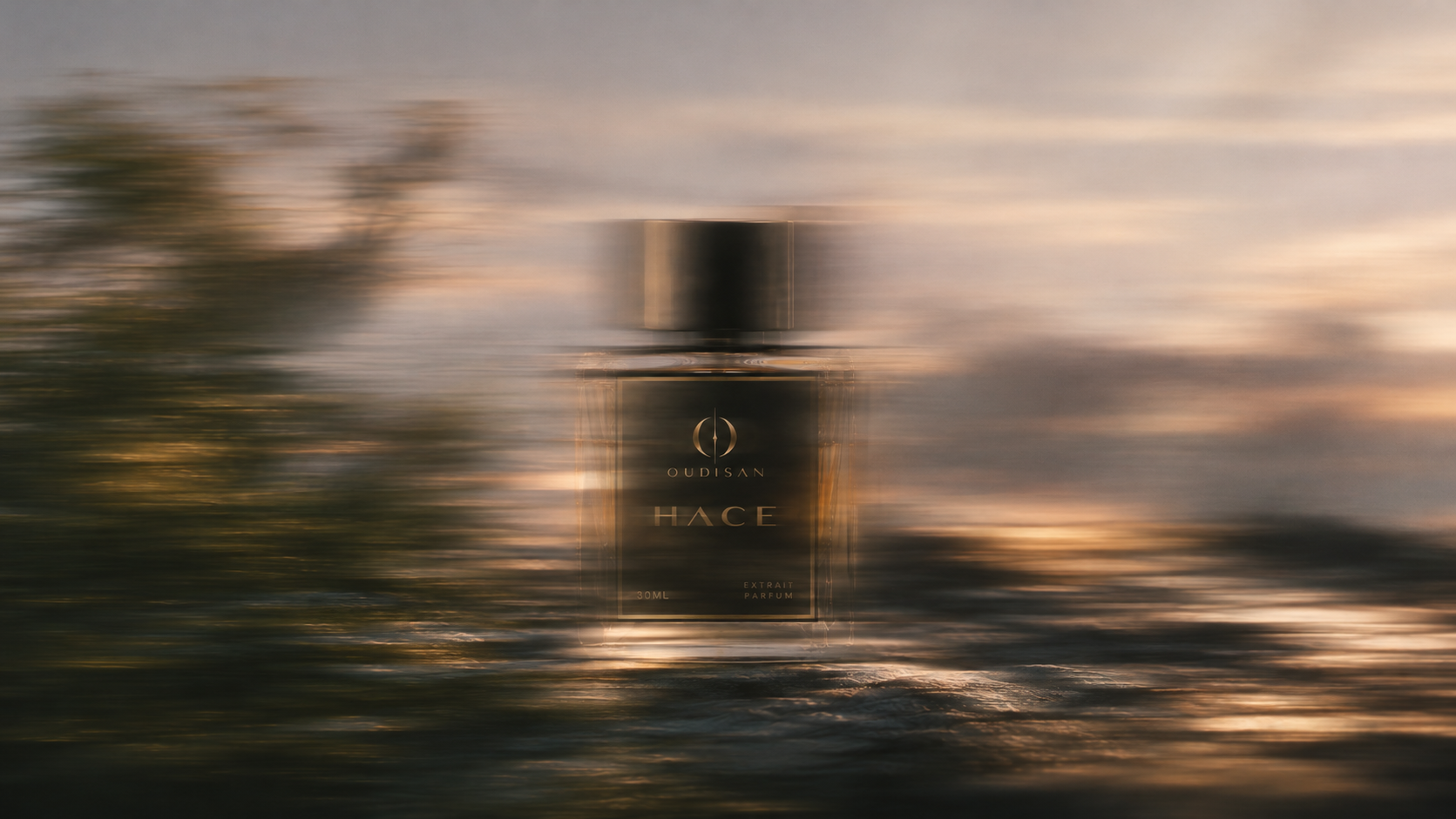 Oudisan Hace extrait de parfum seen through a motion-blurred sunset landscape